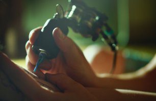 Tattoo master tattooing on the a girl arm.